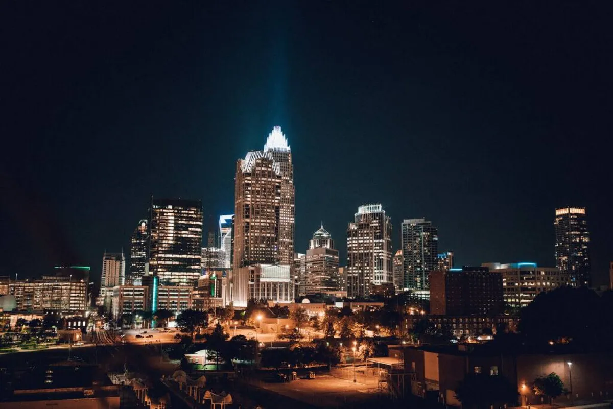 An impressive exterior shot of Charlotte’s city skyline at night, with illuminated buildings against a dark sky. The scene evokes a sense of cosmopolitan energy and the opportunities for dining, nightlife, and exploration in the city.
