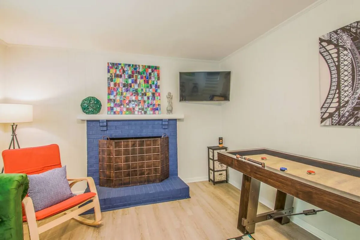 A playful, vibrant interior scene featuring a game table, blue fireplace, and colorful wall art. The space exudes a cozy, joyous mood—perfect for family game nights and creating memories together.