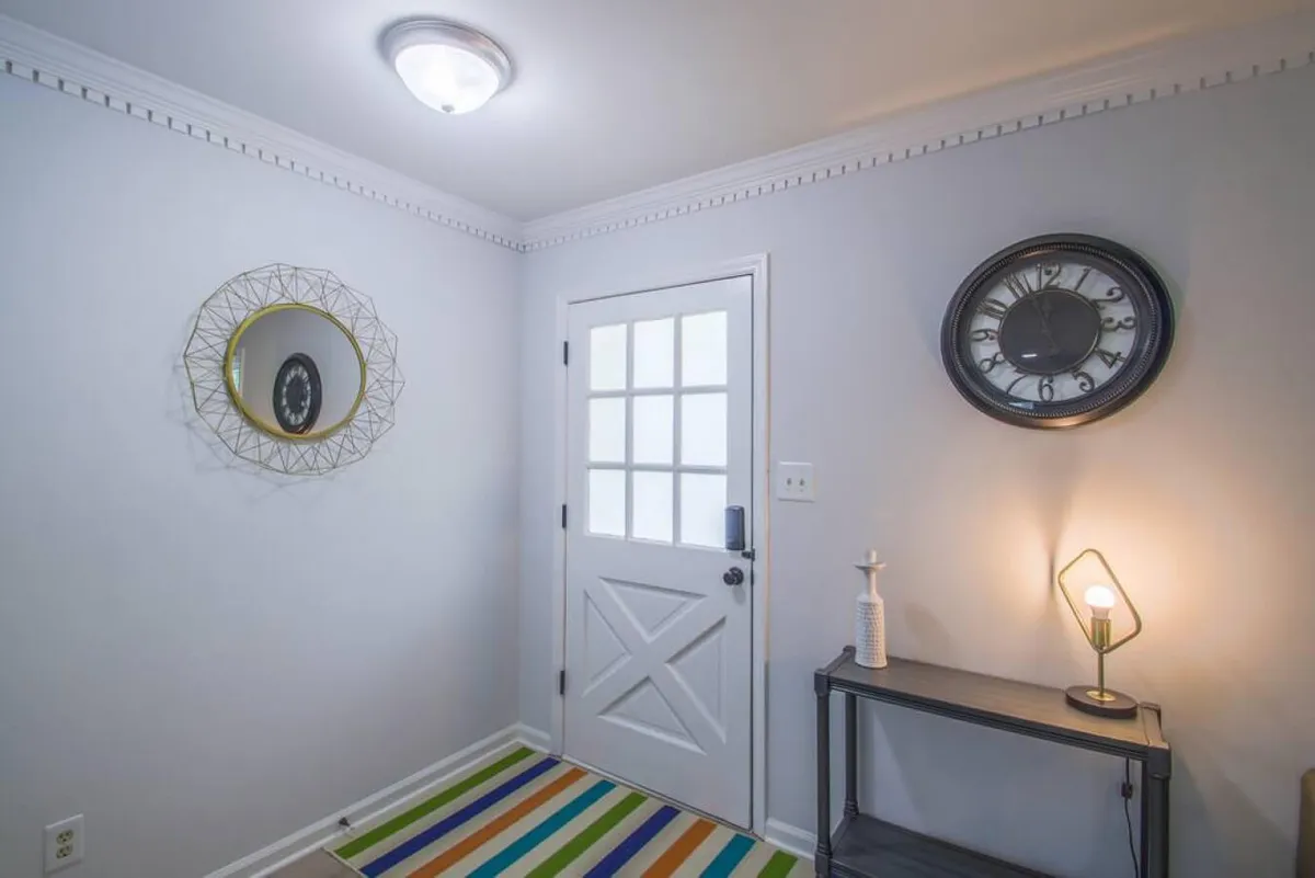 The image showcases a warm and inviting entryway with a console table, mirror, lamp, and clock, offering a welcoming first impression as you step inside. The soft lighting and cozy decor suggest a space ready for intimate moments and shared experiences.