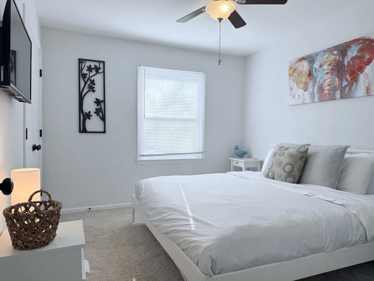 A peaceful bedroom scene with a bed adorned with decorative pillows, elegant wall art, and a nightstand with a softly glowing lamp. The room exudes tranquility and warmth, perfect for unwinding after a long day.